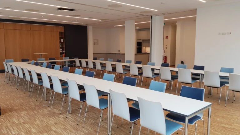 Heller Saal im Fliestedenhaus mit gedeckten Tischen und Stühlen.