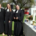 Drei Pfarrpersonen neben einem Altar im Freien beim Tauffest am Otto-Maigler-See.